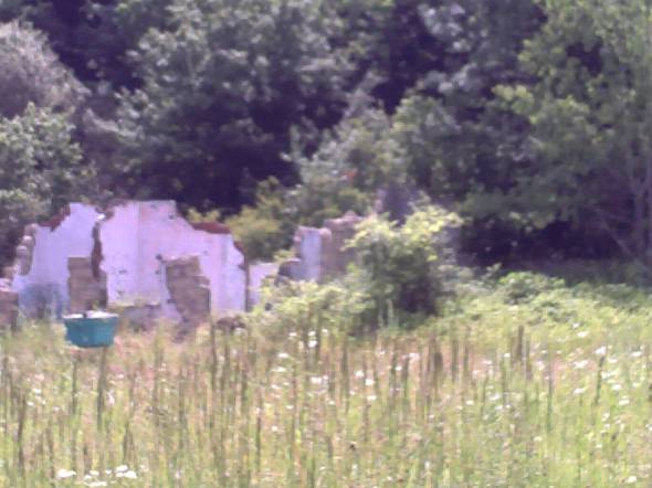 полуразрушенные строения из кирпича и бетона на поляне.